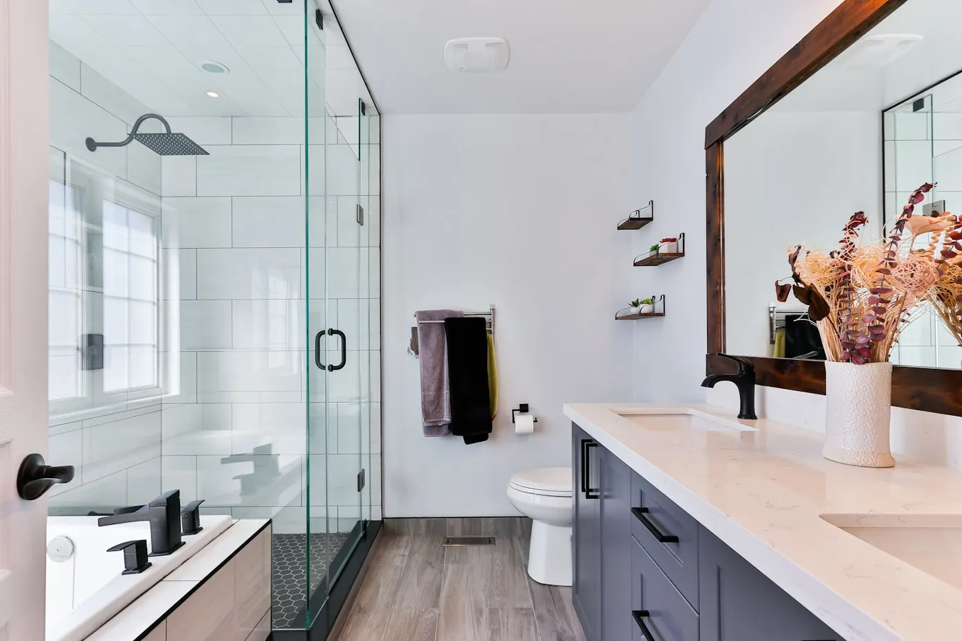 Modern bathroom remodel with a glass shower, quartz double vanity and subway tile.
