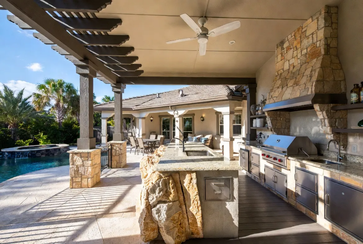 Poolside outdoor kitchen with pergola built by Solid Rock Construction in Naples, Florida